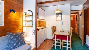 Una habitación acogedora con piso de madera, un sofá, una mesa de comedor con sillas, una zona de cocina y un mapa en la pared.