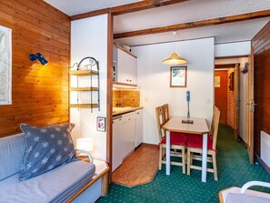 Ein gemütliches Zimmer mit Holzboden, einer Couch, einem Esstisch mit Stühlen, einer Küchenzeile und einer Karte an der Wand.