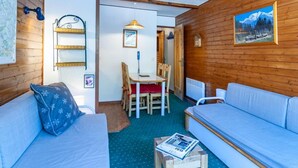 Una habitación acogedora con detalles de madera, un sofá, una mesa con sillas y una cama.