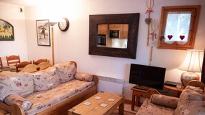 A cozy living room with a sofa, a coffee table, a TV, and a small table with a lamp. - 150m from shops, view parking, balcony, tv, 44m², Méribel-Mottaret (Méribel - Les Allues)