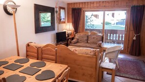 A cozy room with a wooden dining table, a sofa, and a TV. - 150m from shops, view parking, balcony, tv, 44m², Méribel-Mottaret (Méribel - Les Allues)
