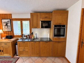 A compact kitchen with wooden cabinets, a microwave, an oven, and a sink. - 300m from ski slopes, view parking, balcony, tv, 44m², Méribel-Mottaret (Méribel - Les Allues)