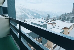 A balcony with a view of snow-covered buildings and mountains. - 10m from ski slopes, 4th floor, balcony, tv, 17m², Les Menuires (Les Menuires)