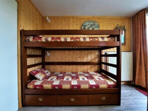 A bunk bed with a quilted mattress and a wooden headboard.