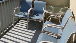 A balcony with a view of the beach, featuring a table and several chairs.