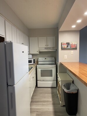 Kitchen equipped with a refrigerator, microwave, double oven, and trash bin.