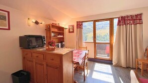 Une cuisine chaleureuse avec des meubles de rangement en bois, un four à micro-ondes et un coin repas comprenant une table et des chaises.