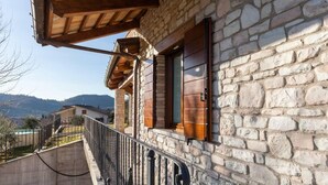 Un bâtiment en pierre doté d’un balcon, d’une rambarde en métal et offrant une vue sur le paysage environnant.