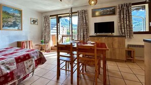 Una habitación acogedora con cama, una mesa de comedor con sillas, televisor y zona de cocina.