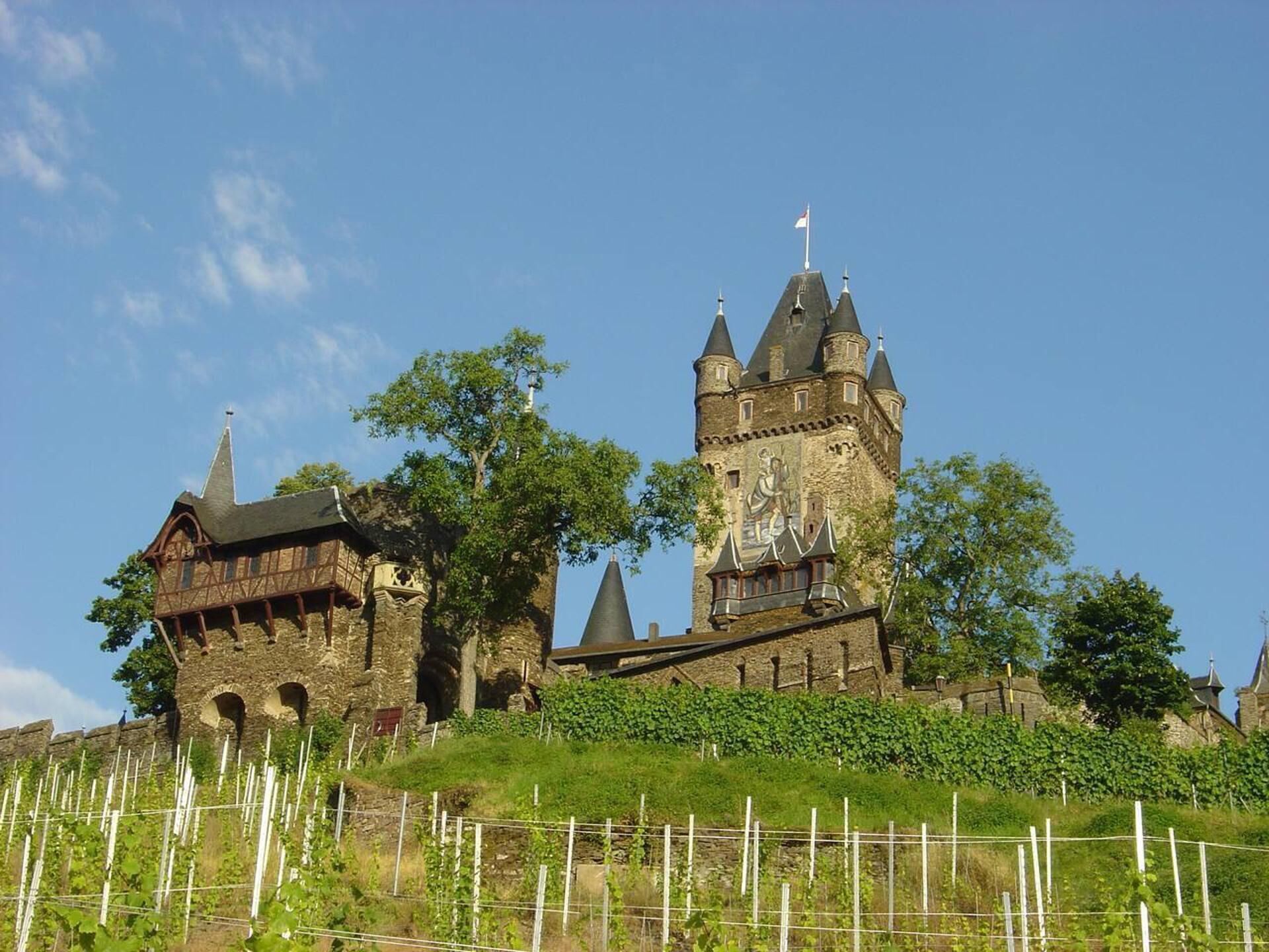 A historic castle with multiple towers and a prominent central tower featuring a mural.