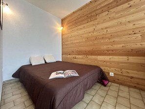 Ein Schlafzimmer mit einem hölzernen Kopfteil, einer braunen Bettdecke und einer Zeitschrift auf dem Bett.