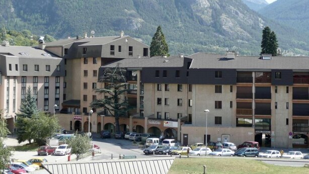 A multi-story hotel with a parking lot in front, surrounded by mountains. - 350m from ski slopes, 3rd floor, view mountain, tv, 25m², Serre Chevalier (Briançon)