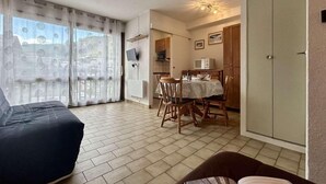 A living room with a sofa, a dining table with chairs, a kitchen area, and a wardrobe. - 350m from ski slopes, 3rd floor, view mountain, tv, 25m², Serre Chevalier (Briançon)