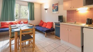 Een kleine keuken met een eethoek, een enkel bed en een televisie.