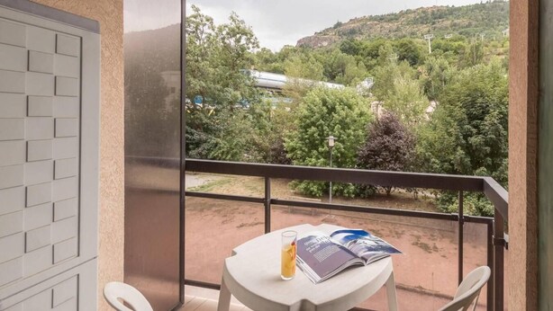 Een balkon met een tafel, stoelen en een tijdschrift.