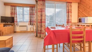 Una camera accogliente con un tavolo da pranzo apparecchiato per due, una televisione e un forno a microonde.