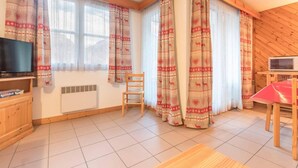 Una stanza accogliente con televisione, un armadio in legno, una sedia e un tavolo.