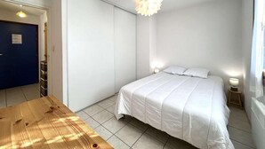 A bedroom with a bed, bedside tables, a wooden table, and a unique ceiling light fixture. - 350m from ski slopes, 2nd floor, balcony, tv, 36m², Serre Chevalier (Briançon)