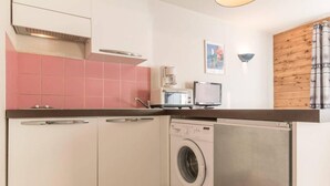 Une cuisine compacte équipée d’un lave-linge, d’une machine à café et d’un petit téléviseur.
