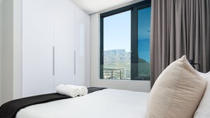 Ein Hotelzimmer mit einem großen Bett, einem Fenster mit Bergblick und einem Balkon.