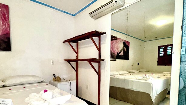 Ein Hotelzimmer mit einem Bett, einer kleinen Holzablage, einem Spiegel und einem weißen Waschbecken.