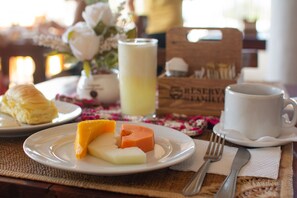 Ein Frühstückstisch mit Käse und Schinken, einem Glas Saft, einem Croissant und einer Tasse Kaffee.