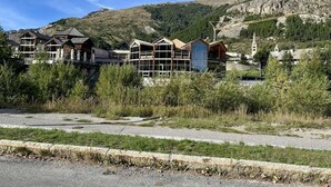 A row of wooden cabins with a mountain backdrop. - Terrace, balcony, parking, 28m², Serre Chevalier (Le Monêtier-les-Bains)