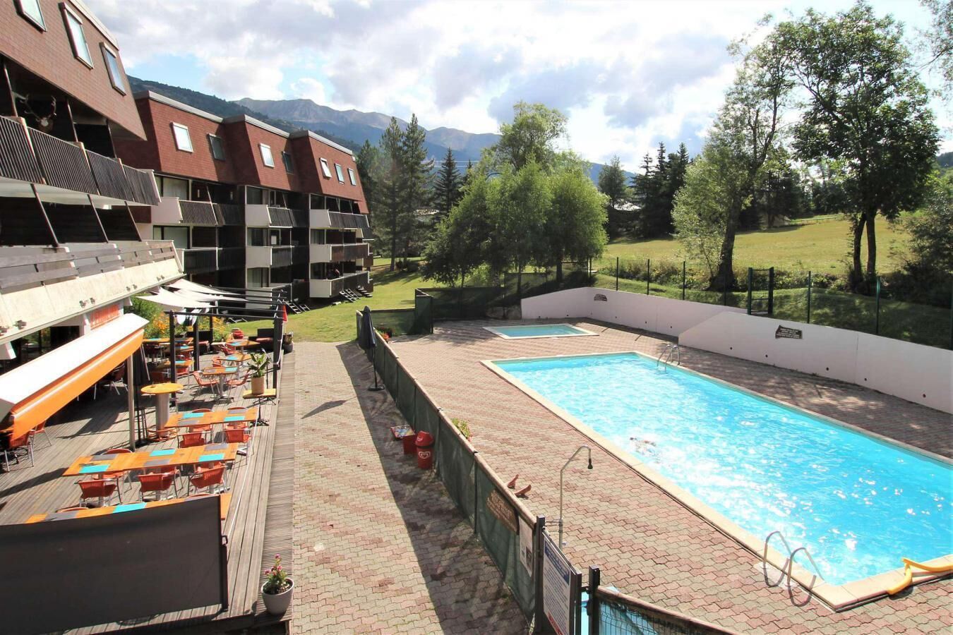 Ein Poolbereich auf dem Dach mit Sitzgelegenheiten und Blick auf Berge.