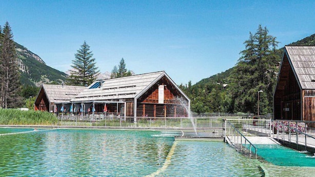 Ein rustikales Holzgebäude mit Schwimmbecken davor.