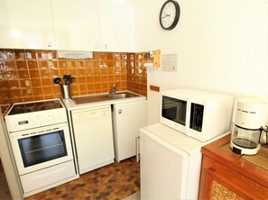 A compact kitchen with a stove, dishwasher, microwave, and coffee maker.