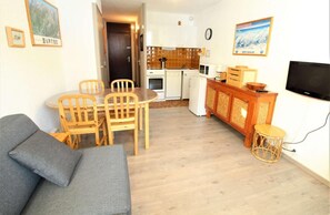 A compact living space with a dining area, kitchenette, and a television.
