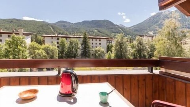 Un balcón con una mesa, una tetera roja y una taza verde.