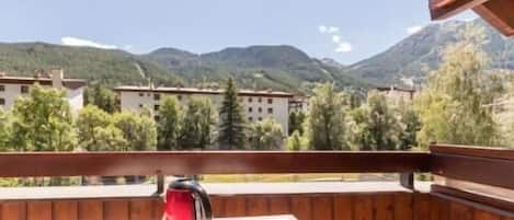Un balcón con una mesa, una tetera roja y una taza verde.