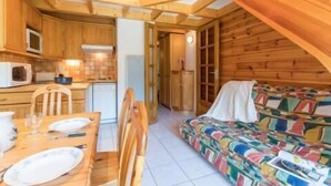 Un acogedor interior de cabaña con comedor, kitchenette y sofá colorido.