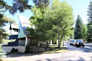 A modern building with a unique triangular roof, surrounded by lush greenery and parked cars. - 260m from resort center, 3rd floor, swimming pool, balcony, 55m², Serre Chevalier (SERRE CHEVALIER)