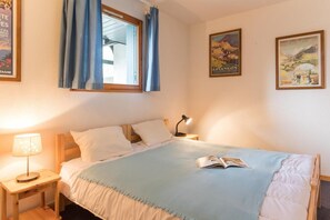 Une chambre à coucher avec un lit, une table de chevet, une lampe et deux affiches au mur.