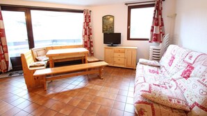 A room with a wooden bench, a sofa, a TV, and a window with curtains.