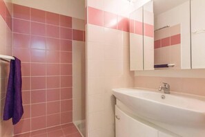 Bathroom features a white sink, modern faucet, and a mirror above, with a shelf for storage.