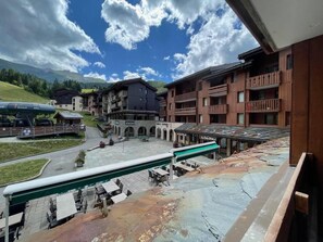 Ein Hotelinnenhof mit Außenbestuhlung, einer Seilbahn und Gebäuden mit Balkonen.