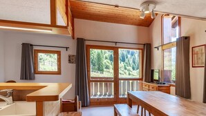 A cozy room with a wooden bench, a table, and a window with a view of trees. - 175m from shops, 3rd floor, view mountain, balcony, tv, 60m², Méribel-Mottaret (Méribel - Les Allues)