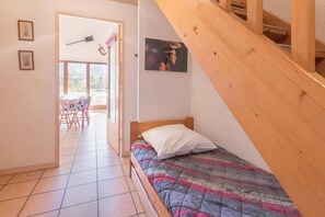 Ein Schlafzimmer mit einem Bett, einer Holztreppe, einem Fenster und einer Tür, die auf einen Balkon führt.