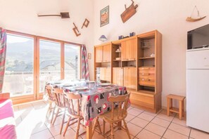 Ein Essbereich mit einem Tisch für vier Personen, Holzschränken und einem Kühlschrank.