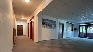 A hallway with a carpeted floor, a door at the end, and a wall-mounted picture.