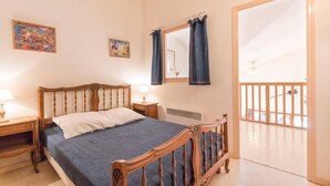 A bedroom with a wooden bed, two bedside tables with lamps, a window with curtains, and a view of the outside balcony.