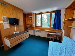 Enjoy a comfortable stay in this compact room with a desk and shelving unit, featuring a large window and a cozy bed.
