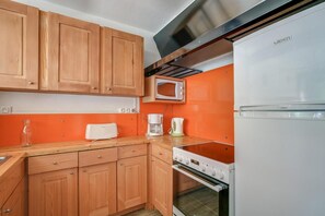 A kitchen with wooden cabinets, a microwave, a coffee maker, and a stove.
