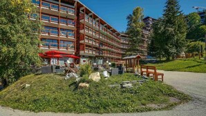 A multi-story hotel with outdoor seating and a landscaped garden area. - 50m from ski slopes, 7th floor, balcony, tv, 60m², Les Arcs (Les Arcs)