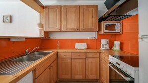 A compact kitchen with wooden cabinets, a microwave, a toaster, and a coffee maker. - 50m from ski slopes, 7th floor, balcony, tv, 60m², Les Arcs (Les Arcs)