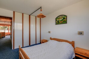 Ein Schlafzimmer mit einem hölzernen Bett, einem Nachttisch, einer Wandleuchte und einem gerahmten Landschaftsbild.