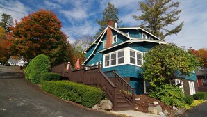A two-story house with a blue exterior, a wooden staircase, and a brick chimney. - Lake George 5 Bed/ 3 Bath home w/ lake & resort access (Lake George)